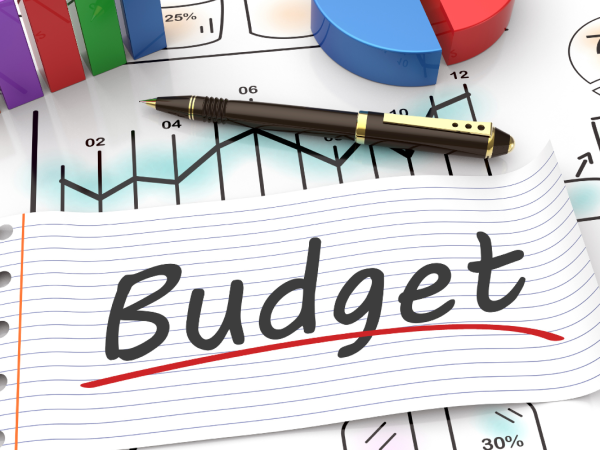 A desk filled with stationary and a sheet of paper that reads 'BUDGET'. A desk filled with stationary and a sheet of paper that reads 'BUDGET'.