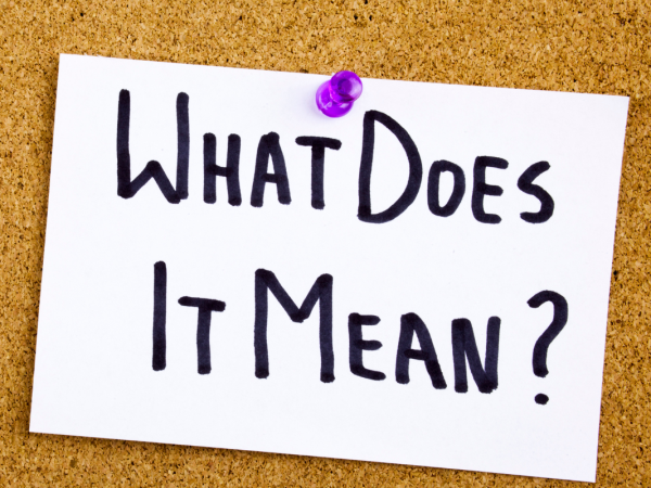 A pin board with a paper attached by a purple pin, the paper reads 'WHAT DOES IT MEAN?'. 