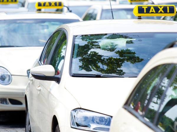 a queue of white cars each one with the word 'TAXI' on top.