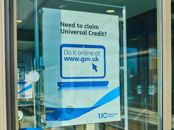 A window with a poster showing that says 'NEED TO CLAIM UNIVERSAL CREDIT?' 