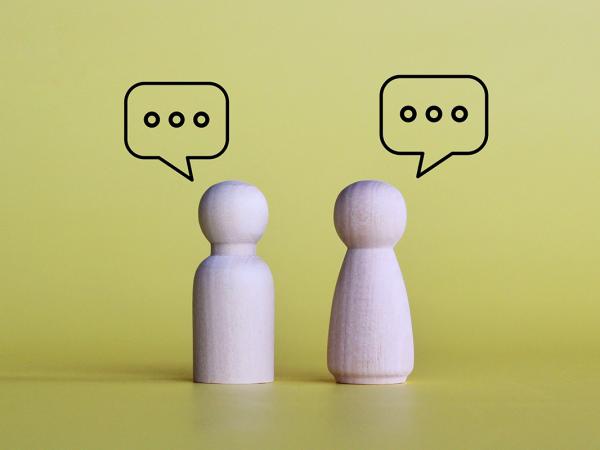 2 wooden figures, each with a speech bubble above them. 
