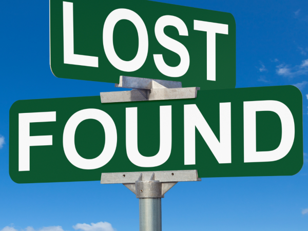 Dark green road signs with the words 'LOST' and 'FOUND' written on them in white text against a blue sky background.