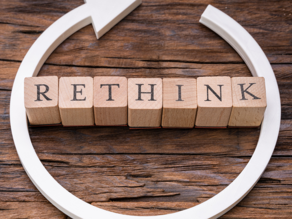 Wooden letters spelling out the word 'RETHINK' with a white circular arrow around it. Wooden letters spelling out the word 'RETHINK' with a white circular arrow around it.