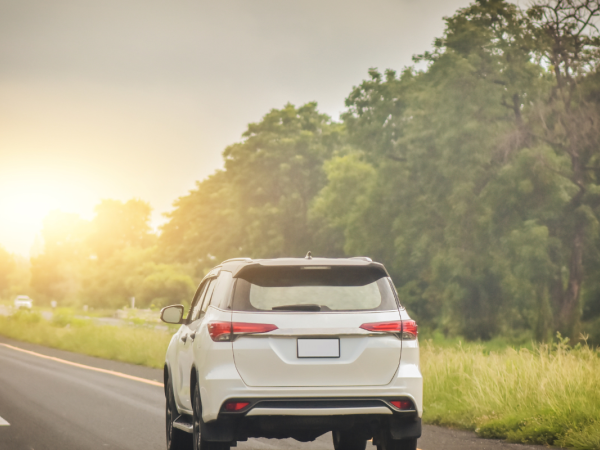 A car driving on a road with a sunrise in the background.