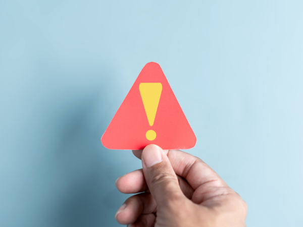 a person holding up a red warning triangle containing an exclamation mark. a person holding up a red warning triangle containing an exclamation mark.