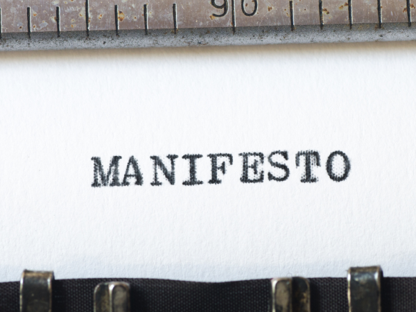 A sheet of paper in a typewriter with the word 'MANIFESTO' typed on it. 