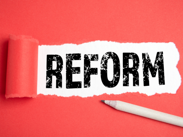 A red paper with a tear in the centre, through the tear the word 'REFORM' can be seen in bold black text A red paper with a tear in the centre, through the tear the word 'REFORM' can be seen in bold black text