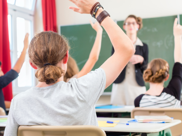 students with hands raised in a classroom