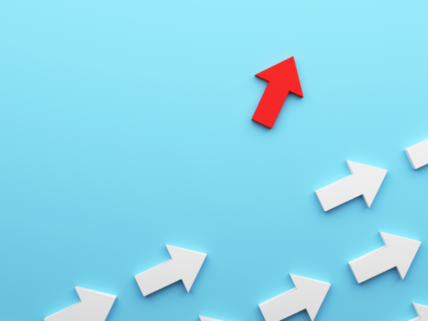 white arrows on a pale blue background with one red arrow pointing a different way.