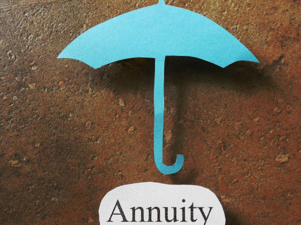 A paper cutout of an umbrella and the word 'ANNUITY' underneath on another piece of paper.
