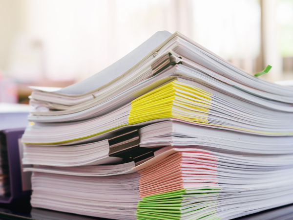 A large amount of files sat on a desk.