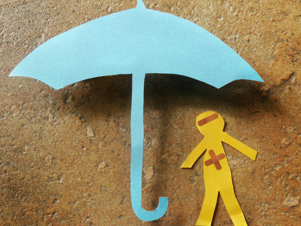 Paper cutouts of a worker stood underneath an umbrella.
