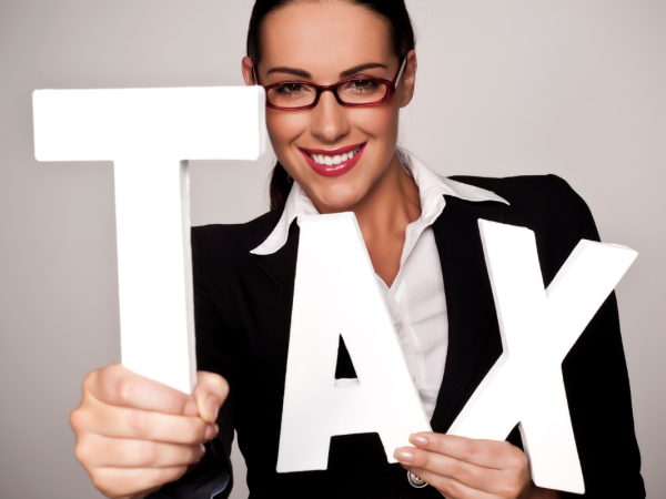 Person holding up white letters spelling out the word 'TAX' 