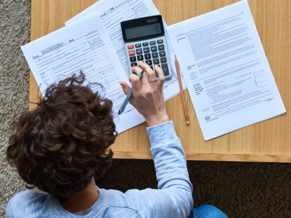 A person sat at a desk with papers and a calculator.