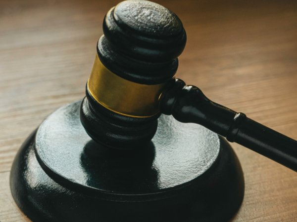 A calculator along with a hammer and gavel sat on a wooden desk A calculator along with a hammer and gavel sat on a wooden desk