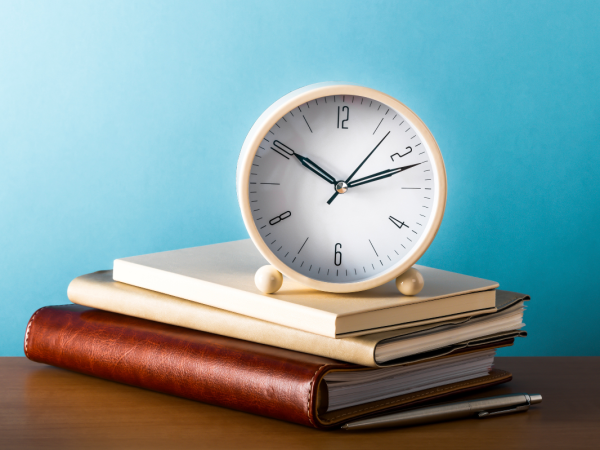 a stack of books with a clock on top 