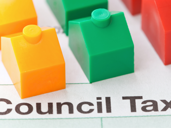 Small coloured plastic houses sat on top of a piece of paper with the words 'COUNCIL TAX BILL' typed on it Small coloured plastic houses sat on top of a piece of paper with the words 'COUNTIL TAX BILL' typed on it