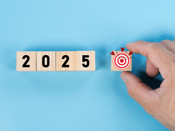 Wooden blocks spelling out '2025' and an additional wooden block with a target with miniature arrows on it. 
