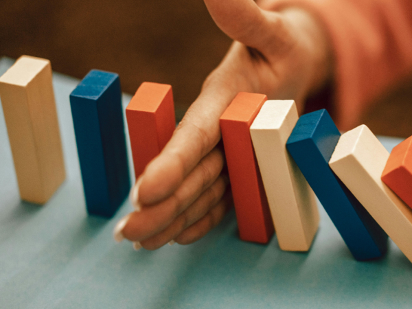 a set of blocks stood on end with a persons hand in the middle, half of the blocks are knocked over, the other half are still stood. a set of blocks stood on end with a persons hand in the middle, half of the blocks are knocked over, the other half are still stood.
