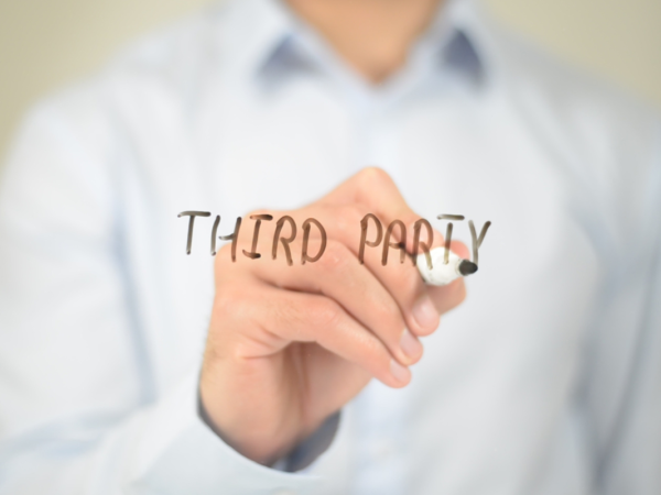 A person writing the words 'THIRD PARTY' on a clear screen with a black pen