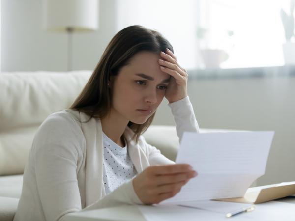 woman holds a document looking distressed