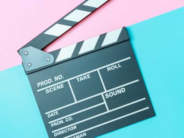 Movie set clapboard against a blue and pink background