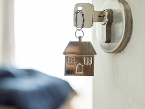 A door with a key in the lock, the keychain is a 2D silver house