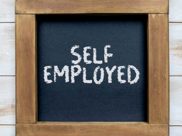 A wooden photo frame with a chalk board inside, on the chalk board the words 'SELF EMPLOYED' can be seen.