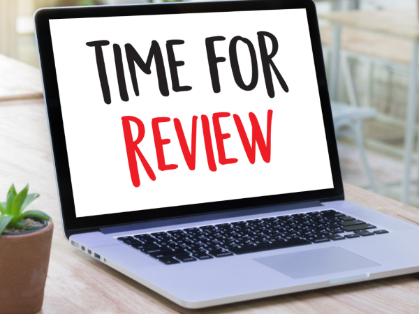 An open laptop with the words 'TIME FOR REVIEW' on the screen