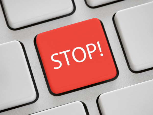 a keyboard showing plain grey keys with one red key in the centre, the red key reads the word 'STOP' in white text