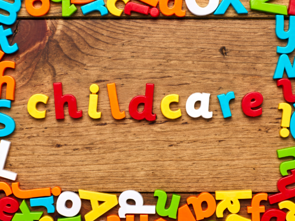 Multi-coloured letters on a wooden background in the centre the letters spell out the word 'CHILDCARE'