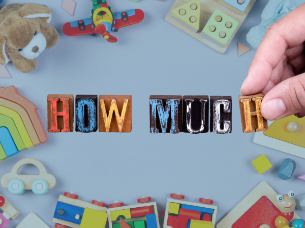 Various childrens items against a pale coloured background and a person holding the words 'HOW MUCH' in the centre