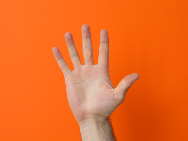 A hand holding up 5 fingers against an orange background