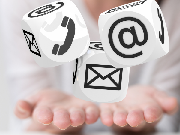 a persons hands holding graphics of dice with icons on each face, shows an email icon, a phone icon and an envelope icon.