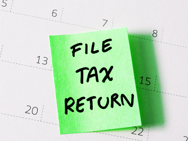 a calendar with a green post it note containing the words 'FILE TAX RETURN' in black ink.