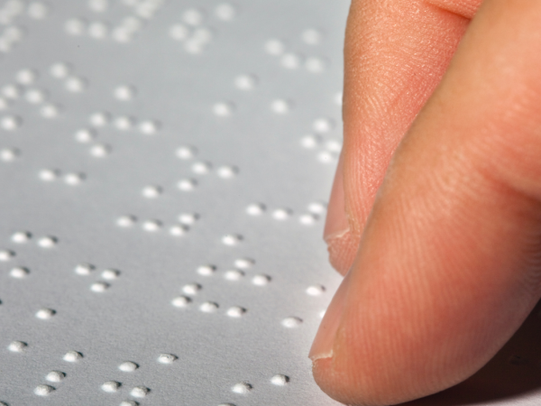 a person reading a sheet of braille 