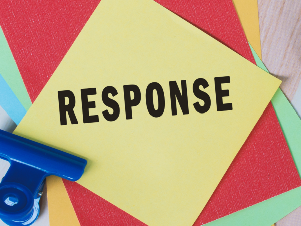 Coloured pieces of paper and desk stationary, the top piece of paper reads the word 'RESPONSE' 