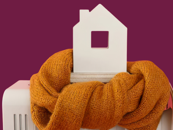 A radiator with a little wooden house on top wrapped in an orange coloured scarf 