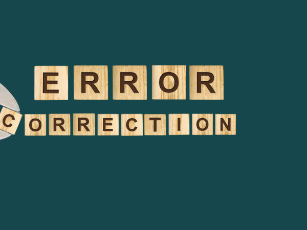A spanner adjusting wooden letter tiles, the letter tiles spell out the words 'ERROR CORRECTION' 