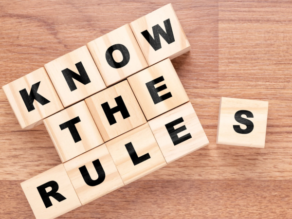 lettered tiles spelling out the words 'KNOW THE RULES' arranged on a wooden floor