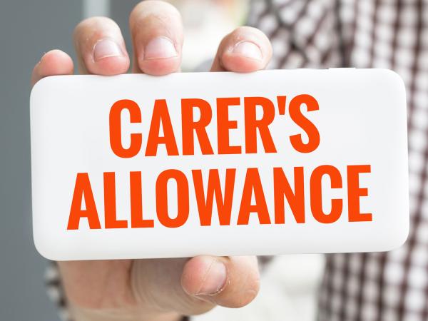 Image of a person hold a sign saying carer's allowance