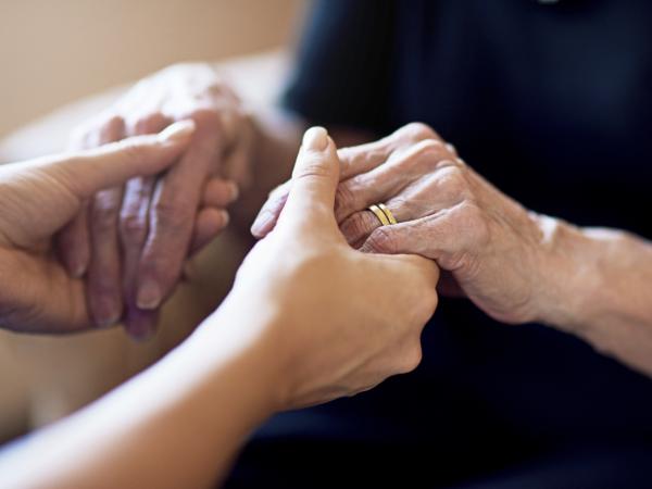 A young person holding hands with an older person. ©istock/PeopleImages