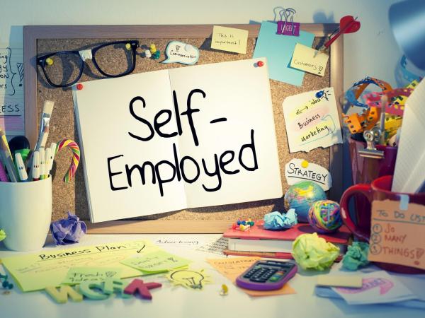 self employed writing in a book in a colourful office