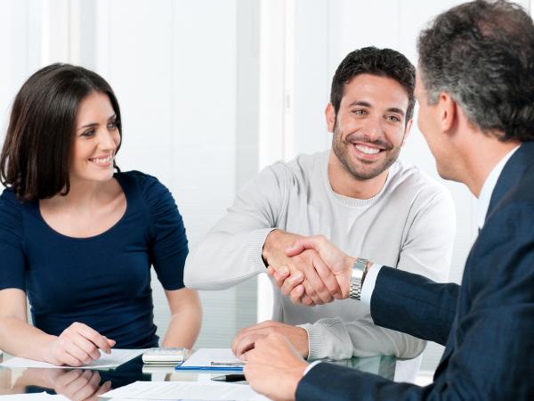 Woman and man, with man shaking hands with man wearing a suit