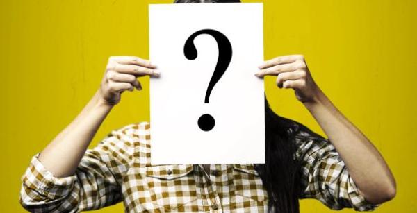 a person holding a piece of paper in front of their face - the paper shows a large black question mark a person holding a piece of paper in front of their face - the paper shows a large black question mark