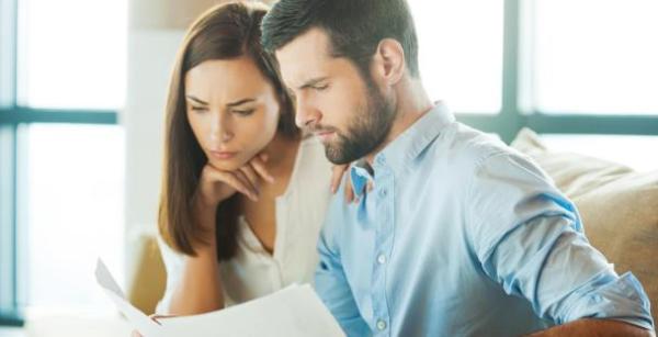 a husband and wife sat side by side looking through paperwork a husband and wife sat side by side looking through paperwork