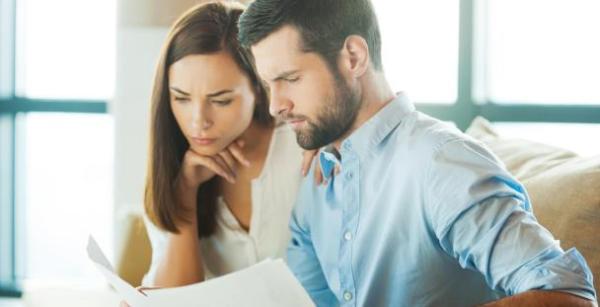 a husband and wife sat side by side looking through paperwork