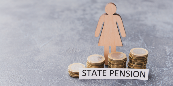 wooden figure of a person stood besides a stack of coins with a typed sign that reads 'state pension'