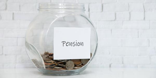 a glass jar with coins inside, on the jar is a handwritten sign saying 'PENSION' 