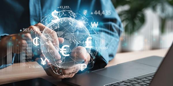 a person sat at his laptop, looking at his mobile phone, a virtual globe can be seen. Around the globe shows all different currencies a person sat at his laptop, looking at his mobile phone, a virtual globe can be seen. Around the globe shows all different currencies